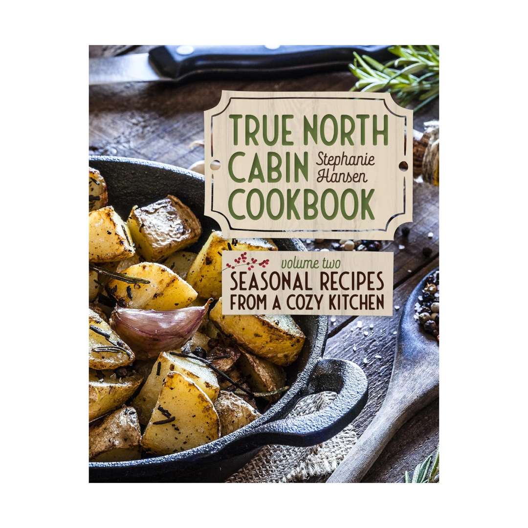 Cookbook titled 'True North Cabin Cookbook - Volume Two. Seasonal Recipes from a cozy kitchen' by Stephanie Hansen with a photo of roasted potatoes.