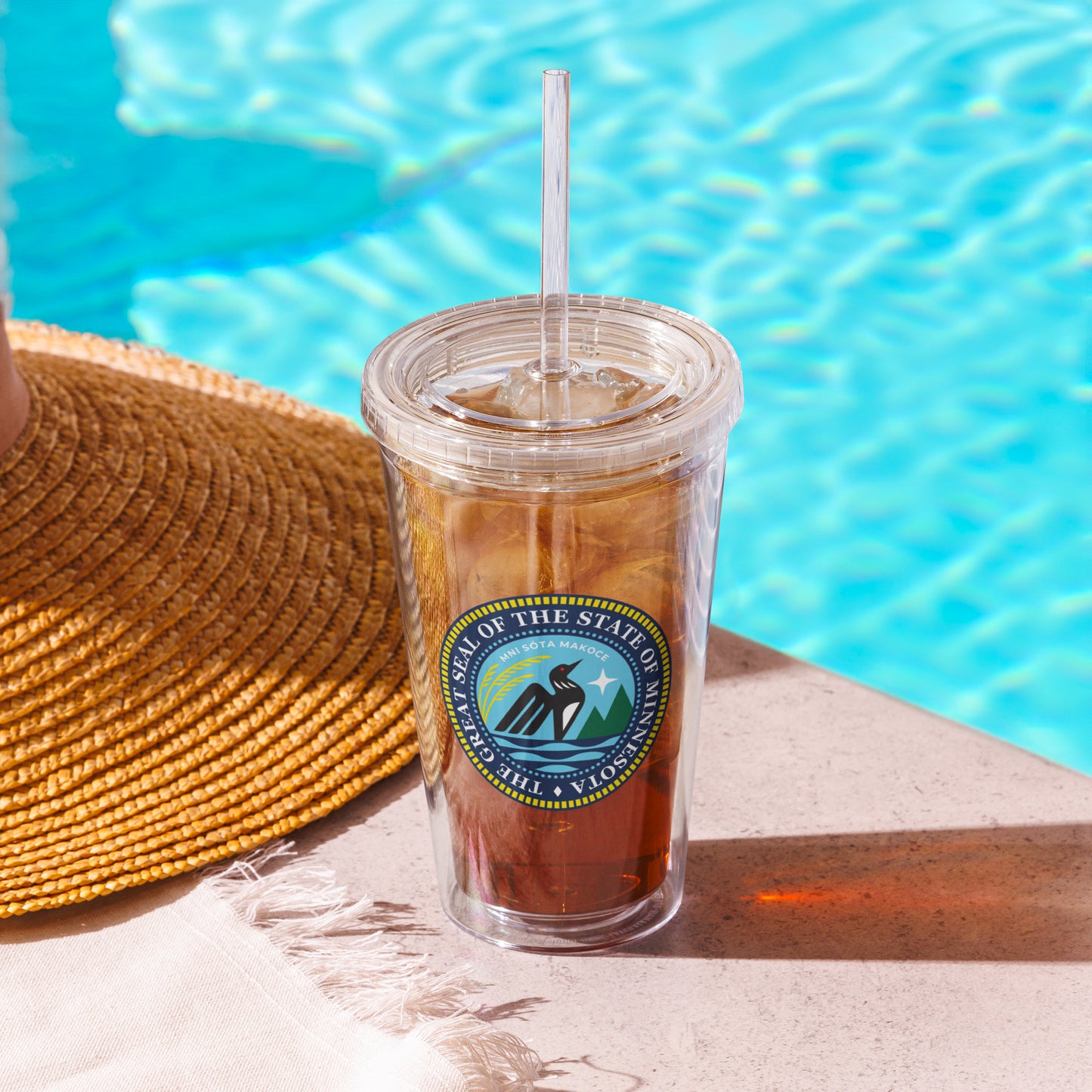 Minnesota State Seal on a clear tumbler with a straw by a pool
