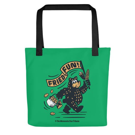 Front view of Green Fair Bear "Fried Fun!" tote bag with black handles. Design of cartoon bear with cookies, corn dog, and roasted corn waving a "Friend Fun!" banner.
